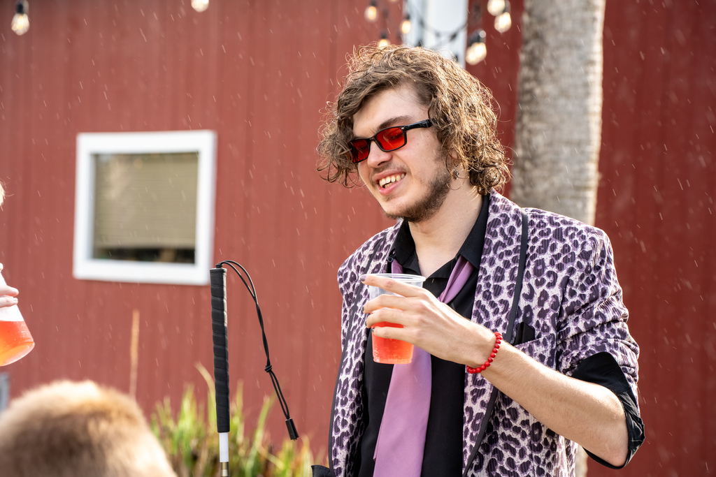 A student dressed in pink and black cheetah color suit smiles outside the barn. 