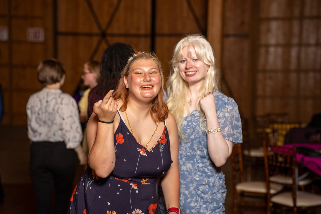 A student smiles with a staff member inside the barn. 