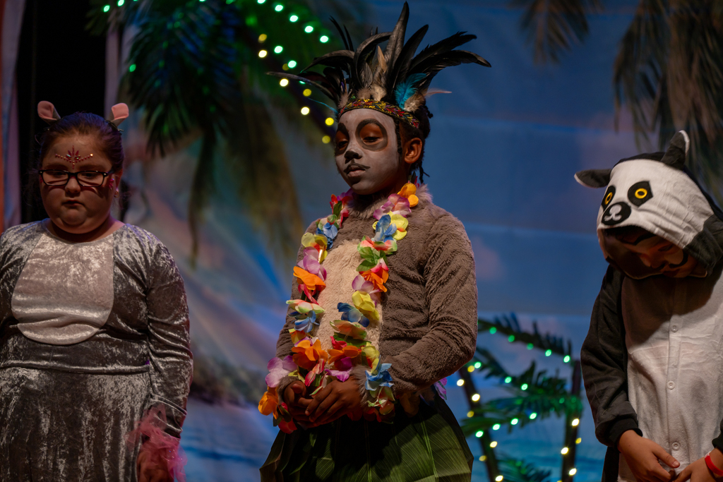 A student dressed like a kola bear wearing a hawiian lei necklace on stage in the music building. 