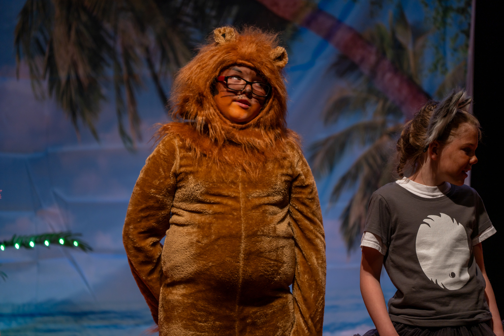 A student dressed like a lion on stage in the music building. 