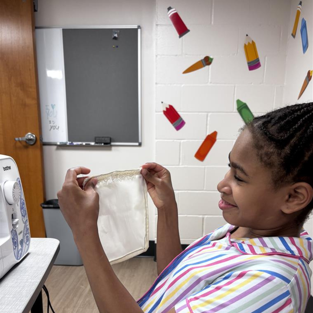 A student is showing off her sewing skills in the dorms. 