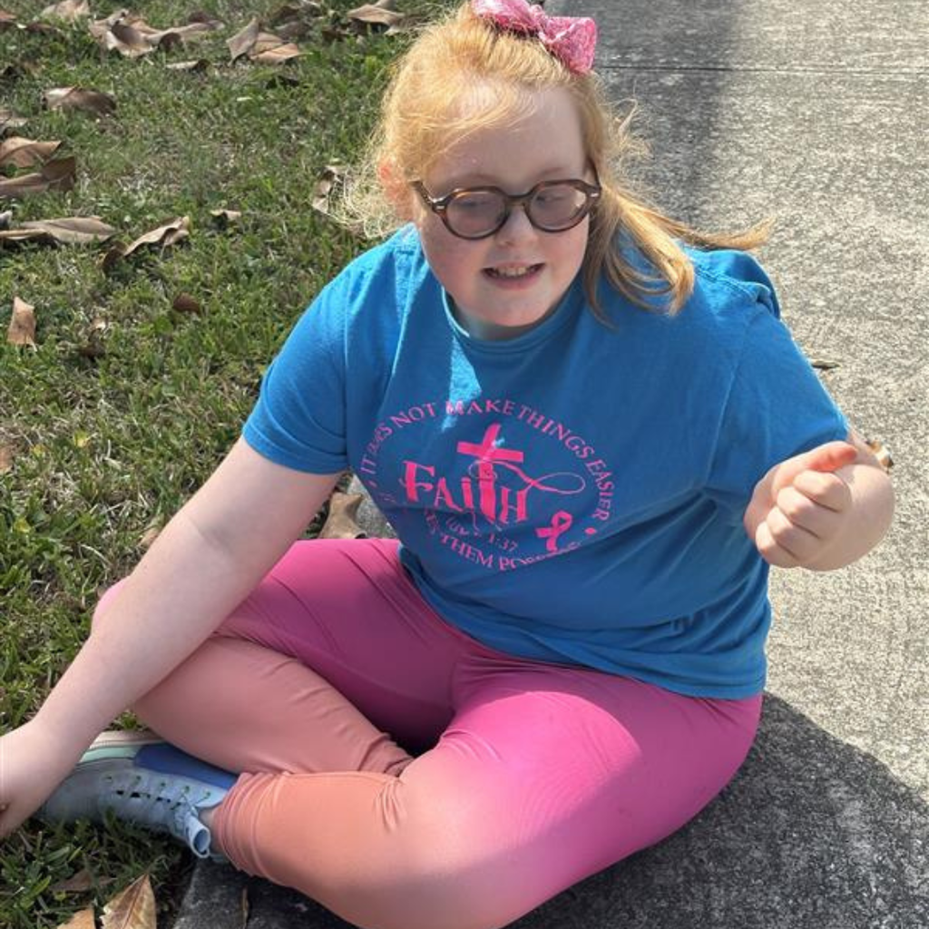 A student is sitting down on the sidewalk outside at the playground. 