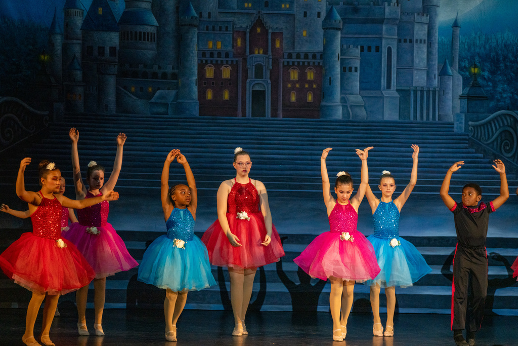 A group of students wearing different color ballet tutus dancing on stage in Kirk.