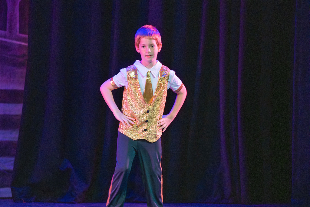 A student is dressed in a gold suit dances on stage in Kirk.