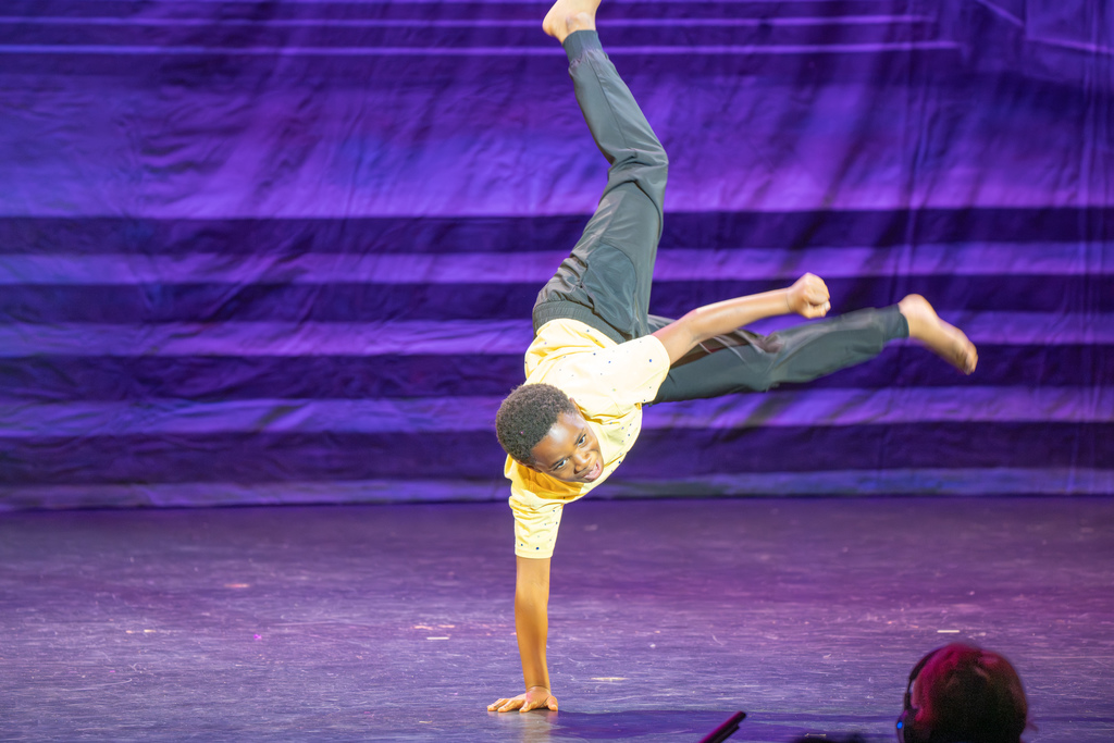 A student doing a handstand on stage in Kirk.