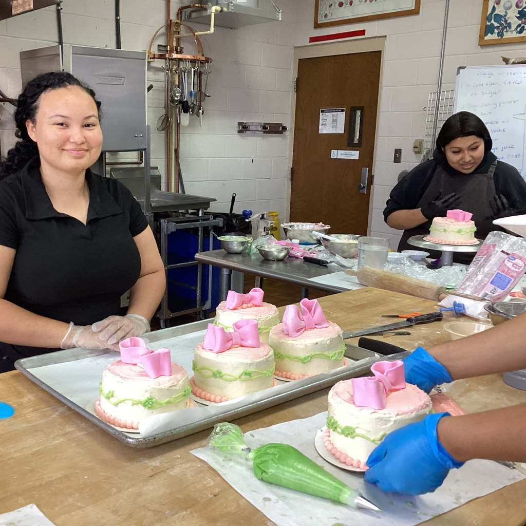 A close up of a student smiling with the Mother Day cakes. 
