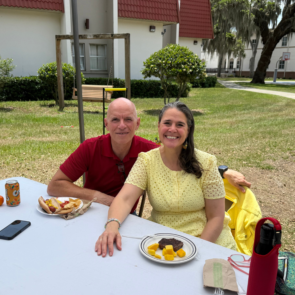President Tracie Snow and her husband sit at a table with their food smile for a photo together.