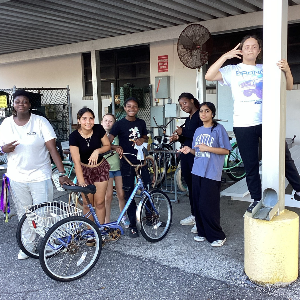 Students smile for a photo by the transportation building. 