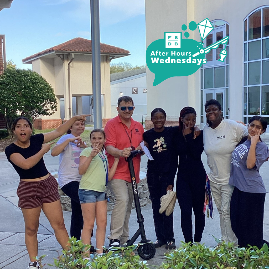 Group of students smile with Matthew who is on his scooter near Pope. 