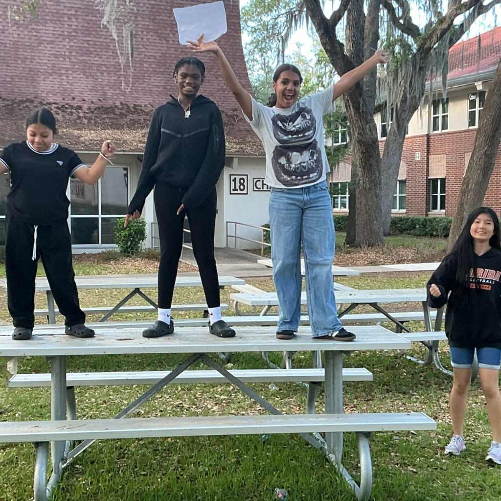Four students near the Capel dancing as their photo is being taken. 