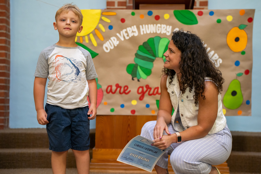 ELC Director looks at an ELC student who is standing on stage in the Chapel. 