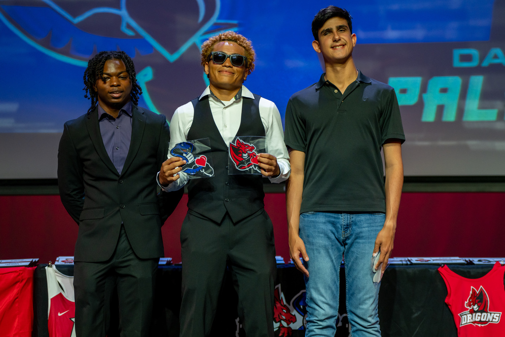 Three students smile on stage together in Kirk.