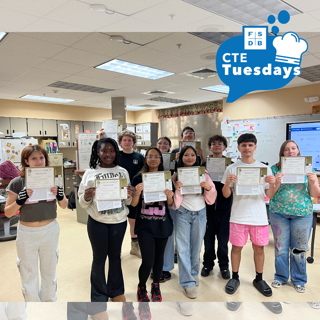 Group of students holding their certification smiling for a photo inside a classroom.
