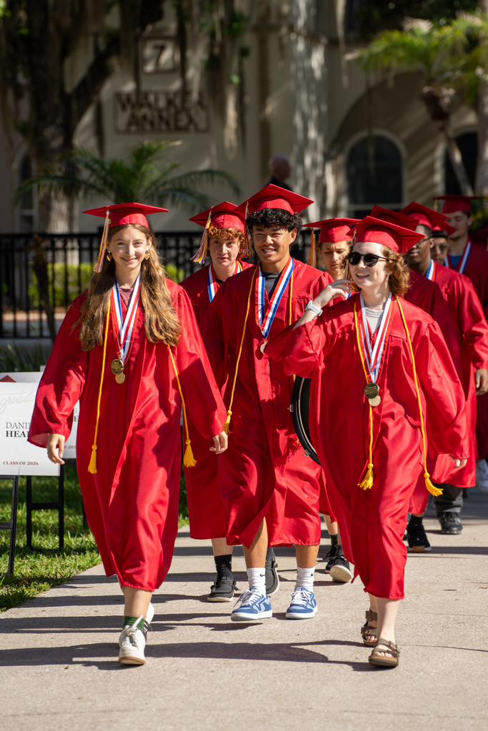 Seniors dressed in red cap and gown walk outside FSDB.