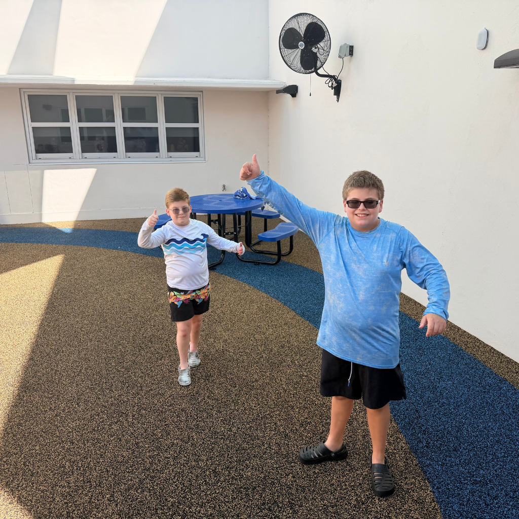 Two students hold a thumbs up for the camera enjoying the new outdoor space.