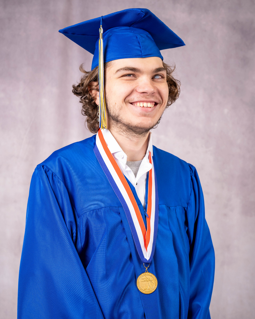 Caden is wearing a blue cap and gown smiling for his photo.