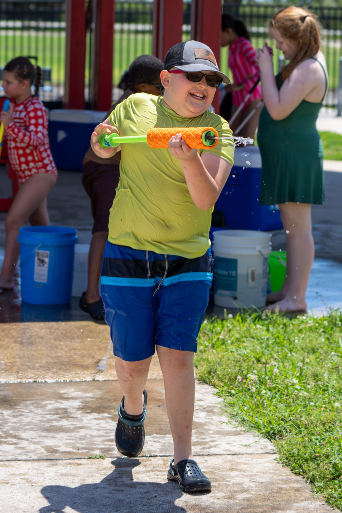A student laughs as he uses the squirt gun to spray someone with water.