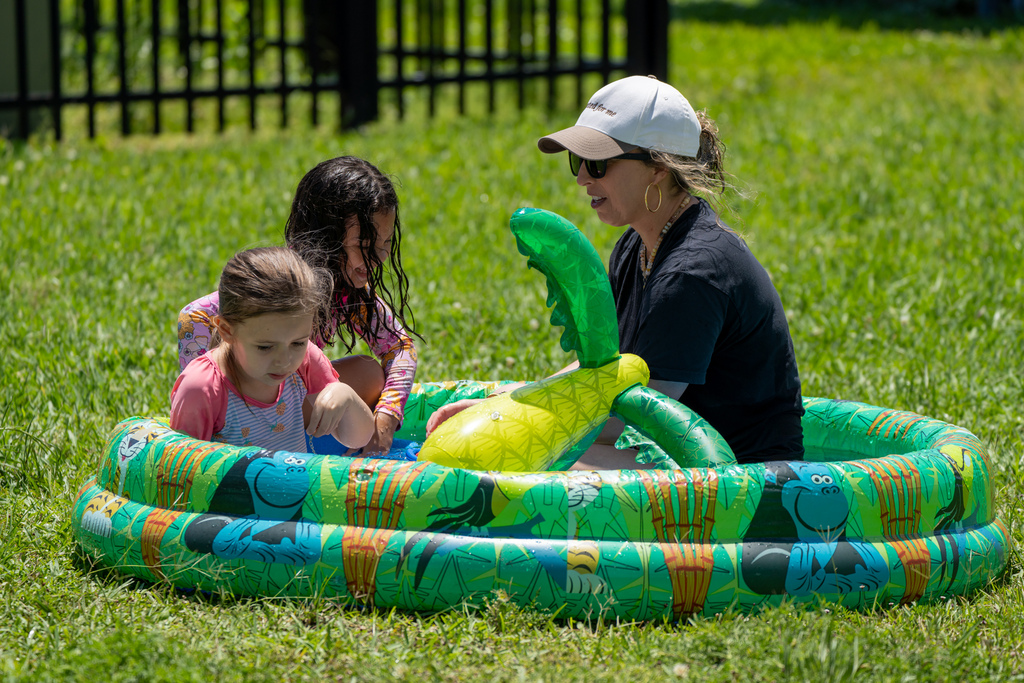 A staff with two students play in a baby pool.