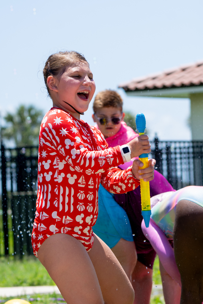 A student laughs as she plays with the pool toys outside.