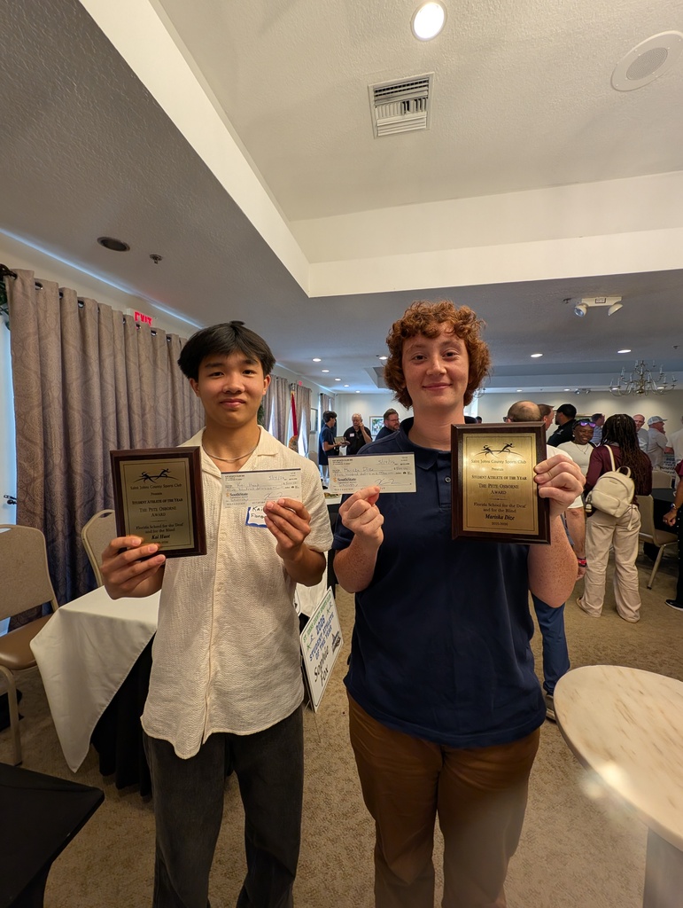 Two deaf seniors are holding their checks and awards inside the St. Johns Sports Club.
