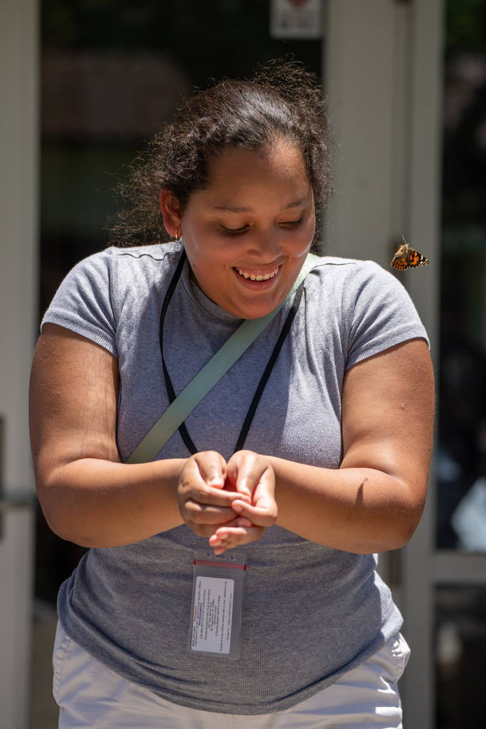 A student holding her hand out for the butterfly.