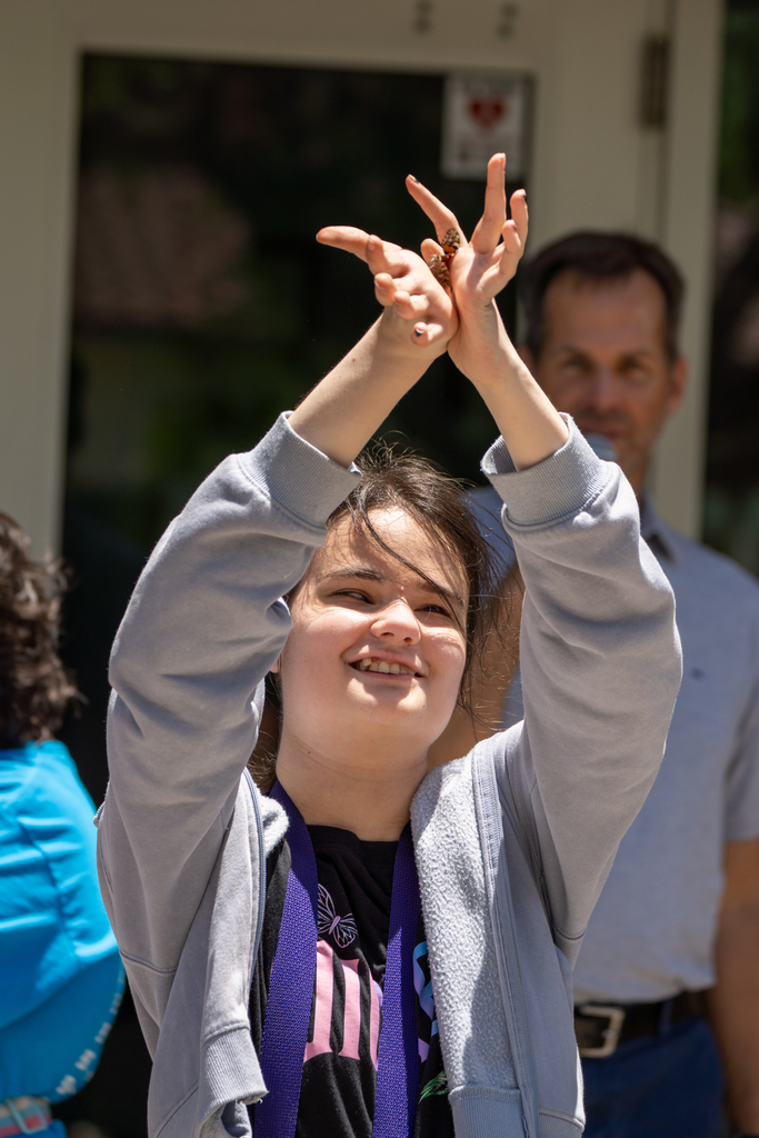 A student holding her hand out for the butterfly.