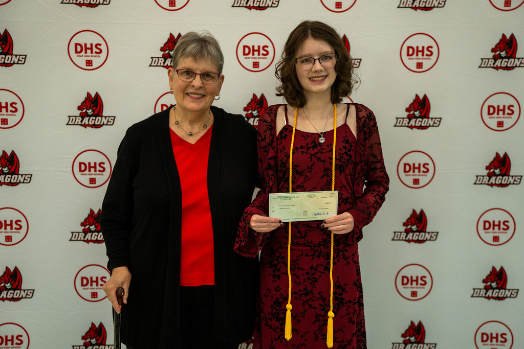 A senior holding her check with the former president of FSDB. 