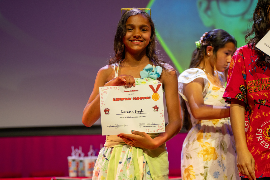 A student smiles with her award on stage in Kirk. 