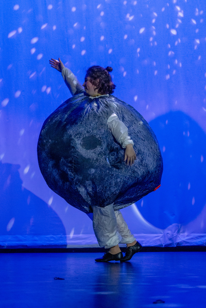 A student dressed like the moon dancing on stage in Kirk. 