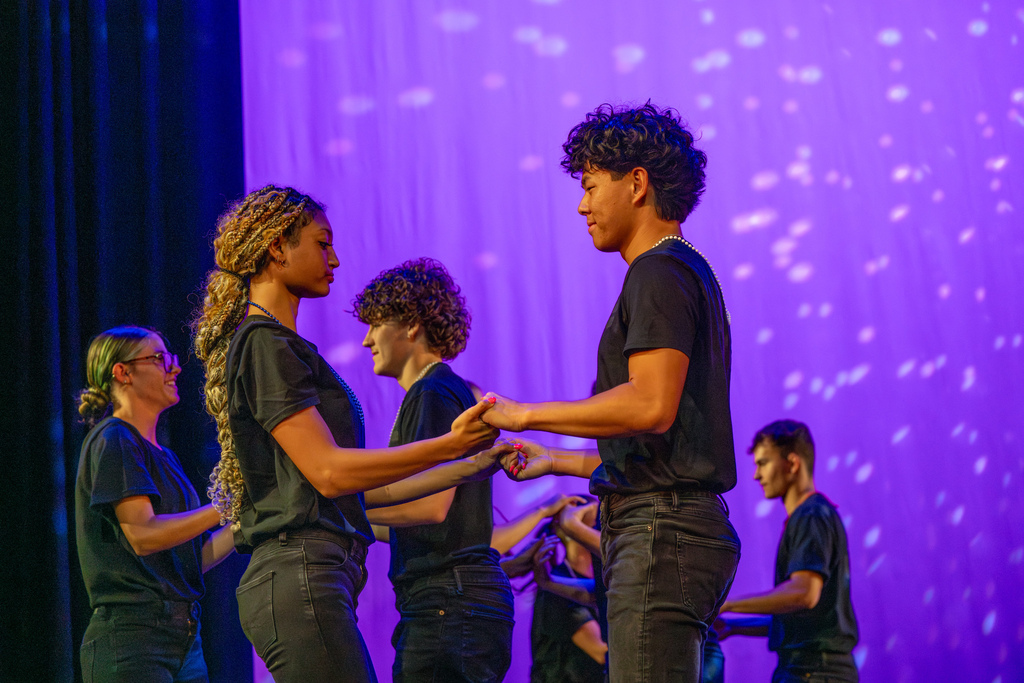 Two students hold hands on stage in Kirk. 