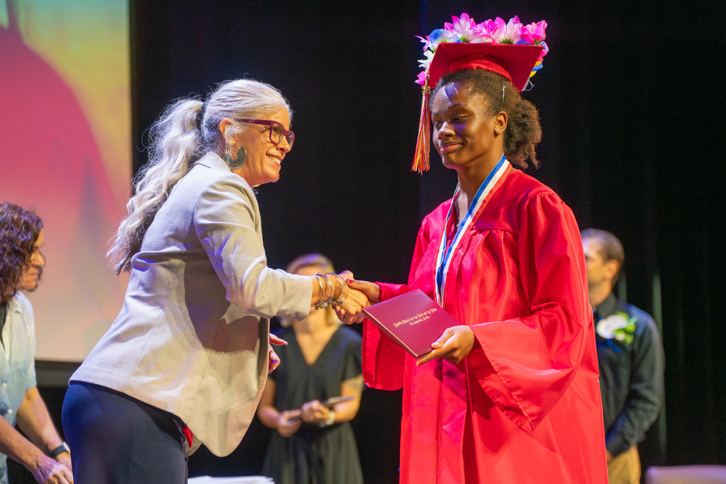 Board of Trustee member hand shakes a deaf graduate student on stage in Kirk.