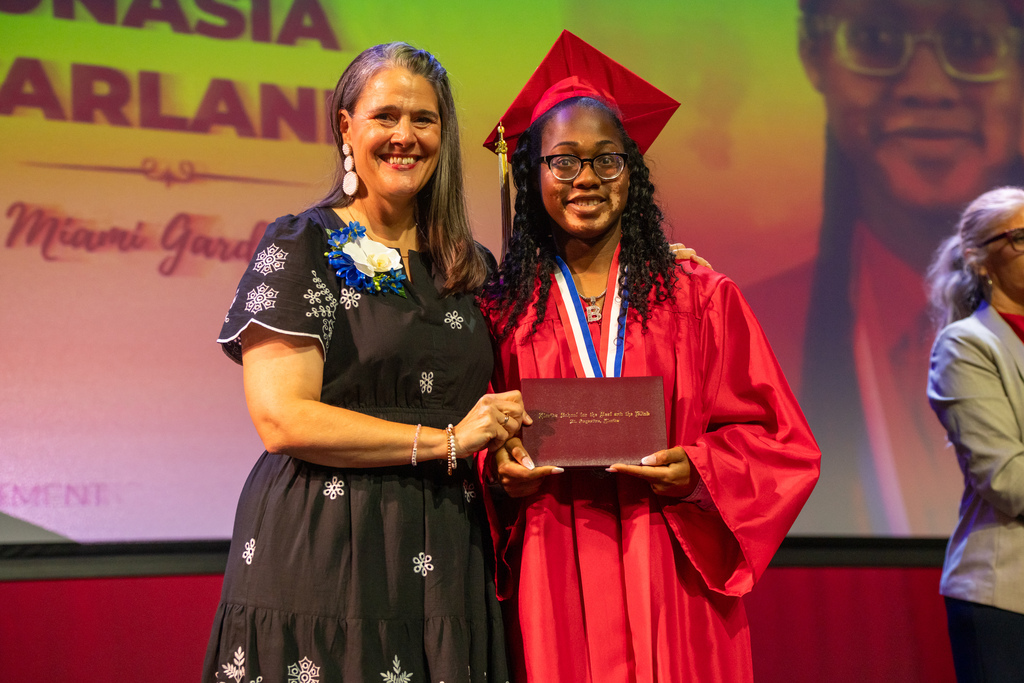 Tracie Snow smiles with a deaf graduate on stage in Kirk. 