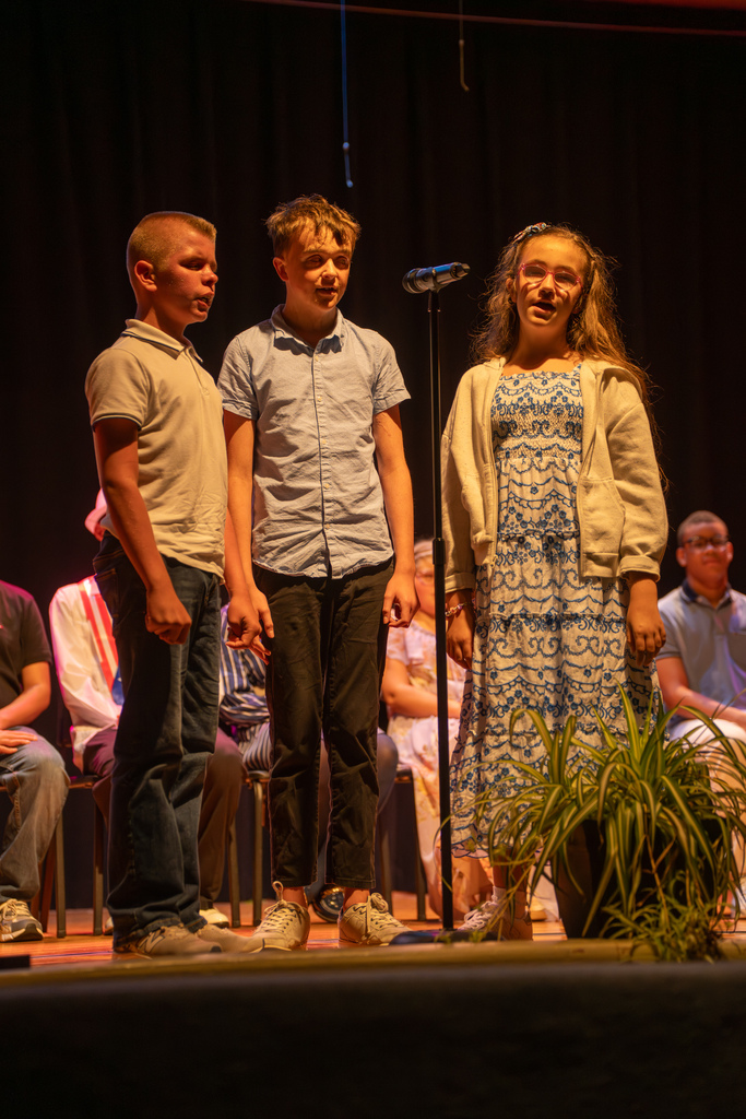 Three students sing on stage for the graduation. 