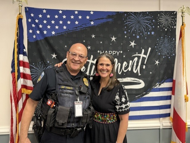 Jerry smiles with President Tracie Snow with the Happy Retirement flag background. 
