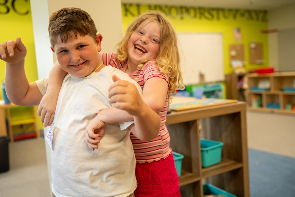 Two students hug for a photo inside the classroom. 