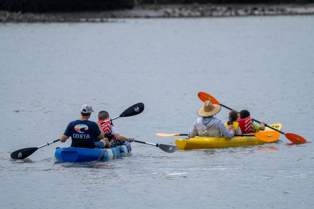 Two sets of kayaks with staff members and campers kayak out on the water. 