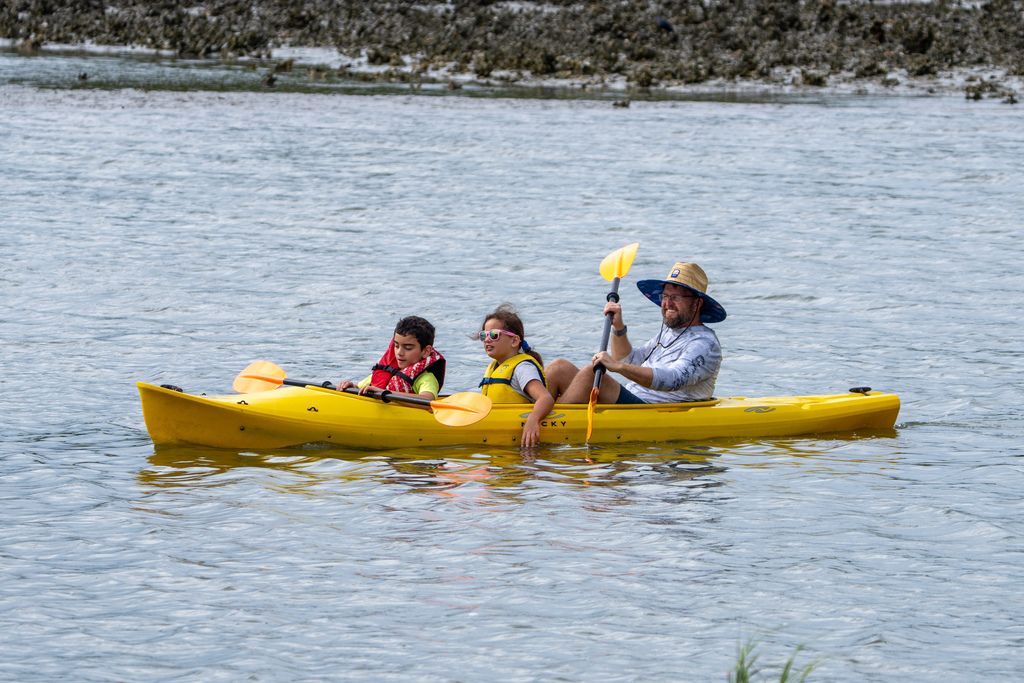 A yellow kayak with one staff member and two campers out on the water. 