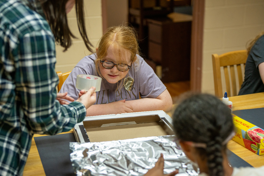 A student listens to the teacher of instructions for the pizza oven box. 