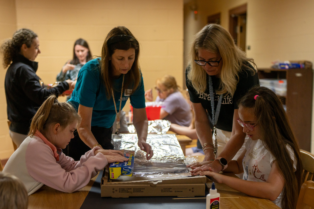 Group of students and staff work together to make a solar oven out of a pizza box. 