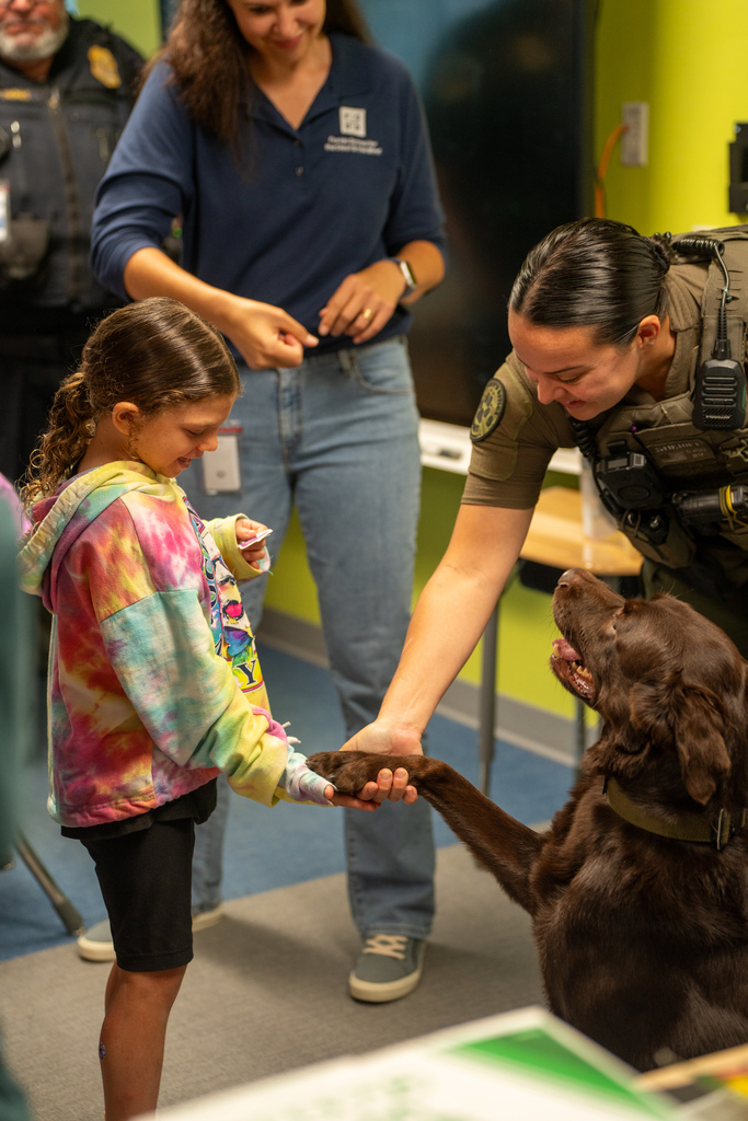 The dog handshakes the camper hand and looks at the sheriff.
