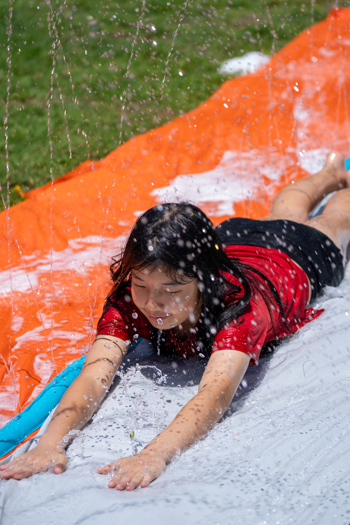Student on a slip and slide outside Palm Row.