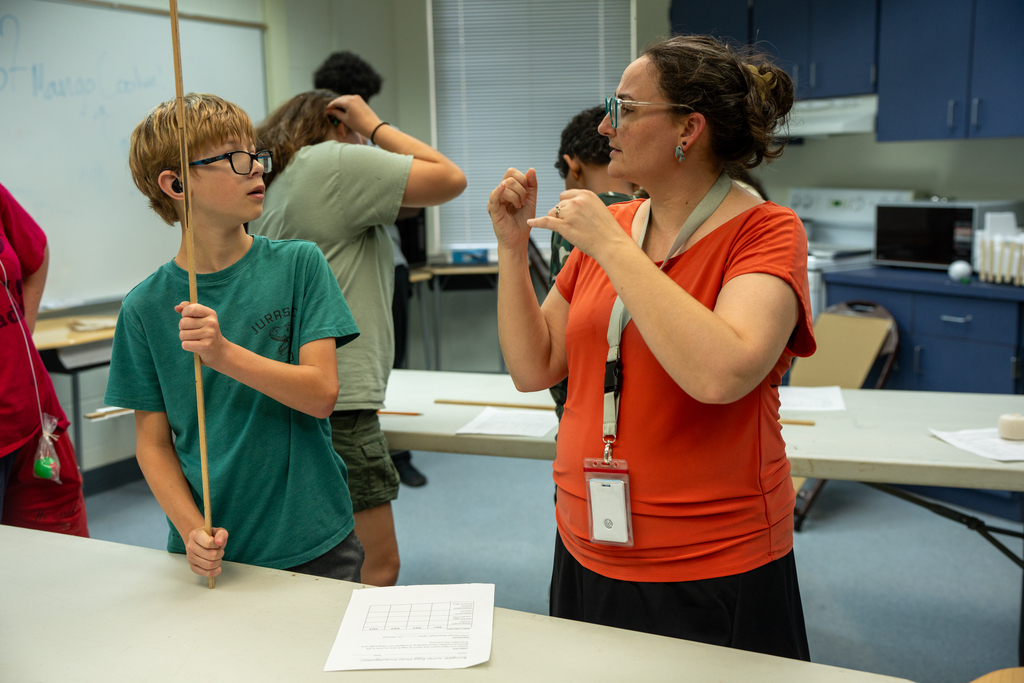 Student and teacher discuss the project inside the classroom.