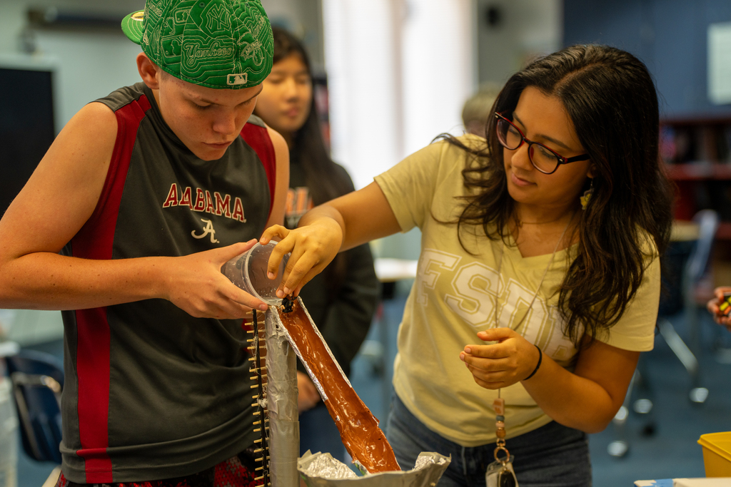 Student and teacher work on an egg drop inside the classroom.