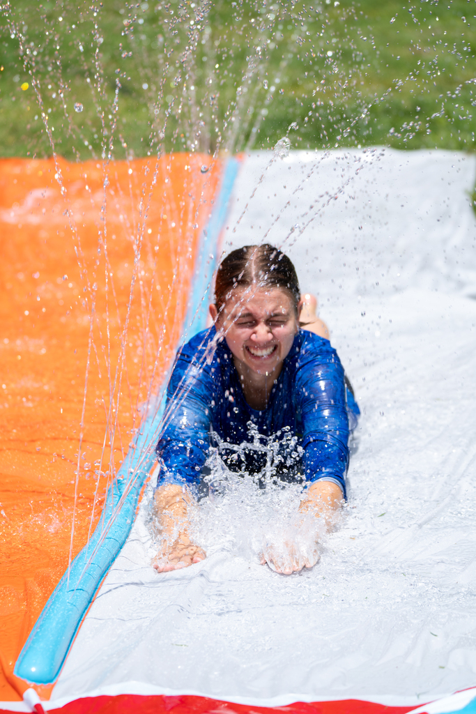 Teacher is on the slip and slide outside Palm Row.