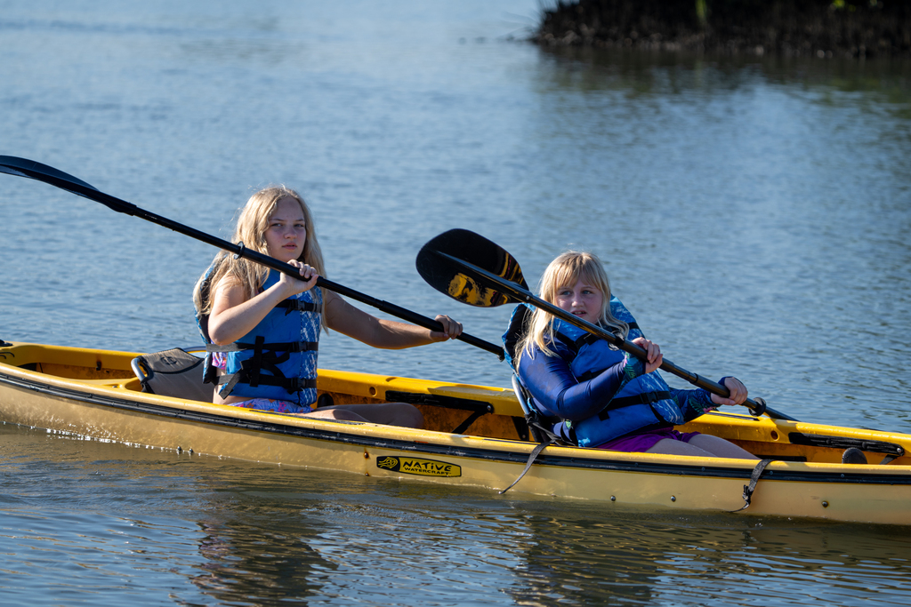 Two campers kayak together out on the water in a yellow kayak.
