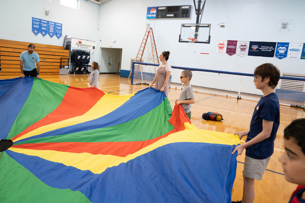 Side shot of students and staff playing with the parachute.