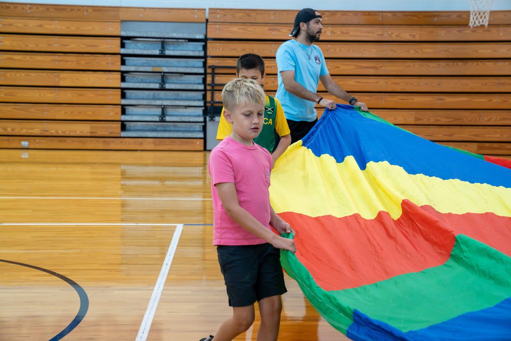 A student holding onto the parachute inside the gym.