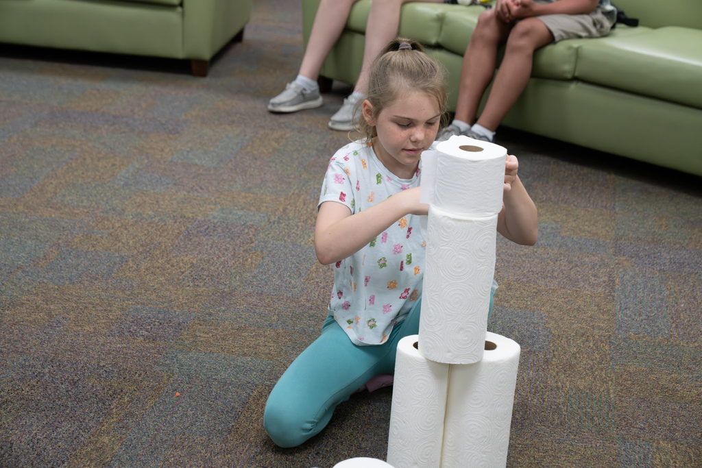 A student is building a tower with paper towels.