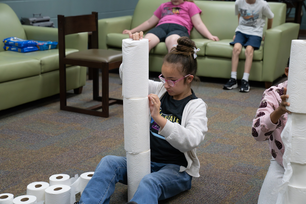 A student is building a tower with paper towels.