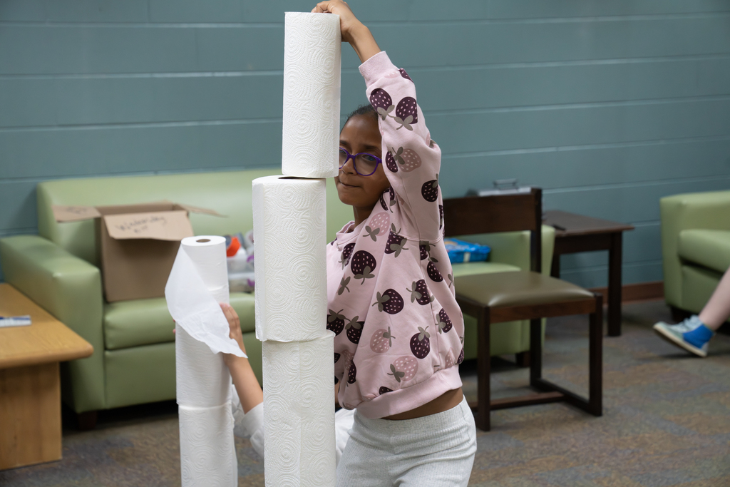 A student is building a tower with paper towels.